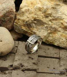 a silver ring sitting on top of a stone floor next to some rocks and stones