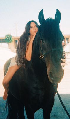 a woman riding on the back of a black horse