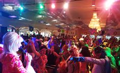 a large group of people dancing in a room with lights and decorations on the ceiling