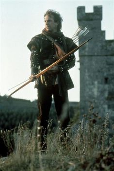 a man dressed in medieval clothing holding two arrows