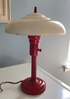 a red table lamp sitting on top of a white counter