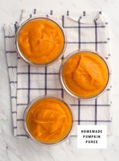 three small glass bowls filled with homemade pumpkin puree on top of a checkered cloth