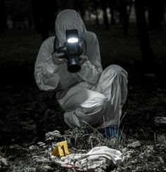 a person in a white suit crouching down holding a camera and looking at something