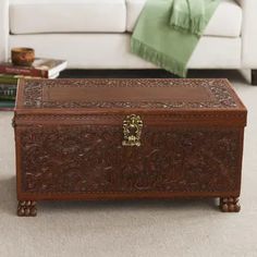 a large wooden trunk sitting on top of a carpeted floor next to a white couch