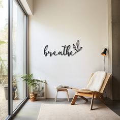 a room with a chair, table and wall hangings that say breathe on it