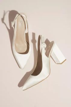 a pair of white high heeled shoes sitting on top of a table