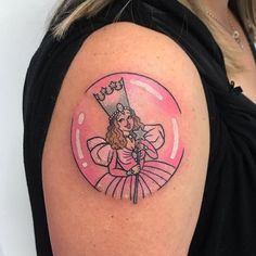 a woman with a tattoo on her arm wearing a tiara and holding a pink bubble