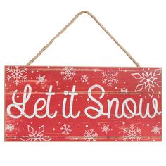 a sign that says let it snow hanging from a rope on a wall with snowflakes