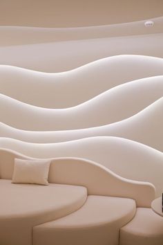 a white couch sitting in front of a wall with curved curves on it's sides