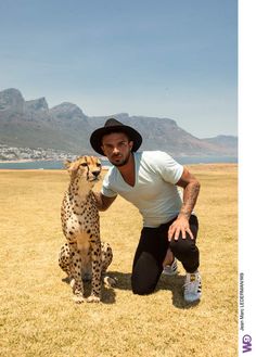 a man kneeling down next to a cheetah