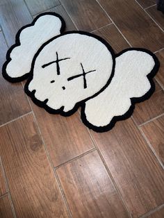 a white rug with a cross on it in the middle of a floor that is made to look like a teddy bear