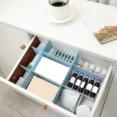 an open drawer with various items in it and a cup of coffee on the side