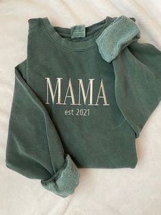 "Time to get comfy! This embroidered sweatshirt will be your new favorite with the bold \"MAMA\" in a modern font and underneath, the year you became a mama 🤍 Customize the sweatshirt with your choice of sweatshirt color from three different brands, as well as the thread color.  In the personalization field, please note the following: 1. Sweatshirt brand and color 2. Thread color 3. Year for est -Sizes available: Adult Small - Adult 2XL (3XL available for select options upon request)  -Fit: noted on pictures for each brand's colors -Machine embroidered  -design centered on chest" Winter Loungewear Tops With Letter Embroidery, Winter Letter Embroidery Sweatshirt For Loungewear, Winter Loungewear Sweatshirt With Letter Embroidery, Relaxed Fit Sweatshirt For Mother's Day Loungewear, Mother's Day Relaxed Fit Sweatshirt For Loungewear, Winter Loungewear Sweatshirt With Embroidered Graphics, Winter Embroidered Graphic Sweatshirt For Loungewear, Winter Sweatshirt With Embroidered Graphics For Loungewear, Mother's Day Crew Neck Sweatshirt With Letter Embroidery