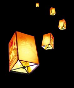 five square lamps are lit up in the dark, with one light turned on and three hanging off