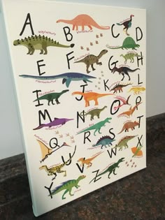 a white canvas with dinosaurs and letters on it sitting on top of a counter