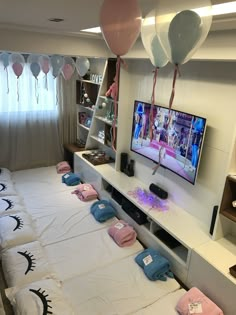 a bedroom with balloons and t - shirts on the bed, television in the corner