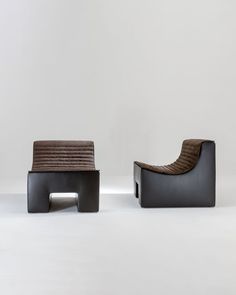 two black and brown chairs sitting next to each other on a white floor with no one in it