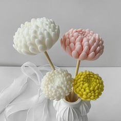 three white vases with flowers in them on a table