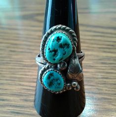 Lovely Pretty Two Stone Turquoise Unique Ring. Turquoise Nugget Stones Are Set In A Raised Bezel With Sterling Braiding Around Each Stone ,Which Highlight The Ring. A Center Sterling Pearl, A Leaf, Three Pearls At The Bottom Of The Leaf Complete The Detailed Design.Handcrafted By A Native American Navajo Artist. Size 8 1/2 Measures 7/8" X 1/2" Weight 6.2 Grams Sterling Silver New ,Never Worn, From Vintage 1980’s Collection. Southwestern Multi-stone Turquoise Ring, Southwestern Blue Turquoise Teardrop Ring, Southwestern Blue Teardrop Ring, Southwestern Teardrop Blue Rings, Vintage Blue Turquoise Ring With Natural Stones, Vintage Turquoise Rings With Natural Stones, Southwestern Turquoise Teardrop Ring, Vintage Turquoise Ring With Natural Stones, Adjustable Vintage Turquoise Ring With Natural Stones