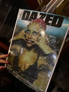 a woman holding up a magazine with the cover of dazed