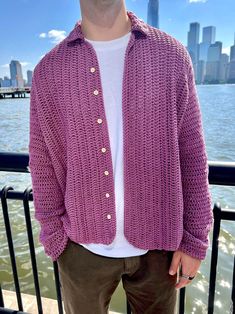 a man wearing a purple knitted cardigan by the water