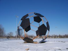 a large metal ball sitting on top of snow covered ground