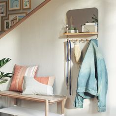 there is a coat rack on the wall next to a bench with pillows and other items