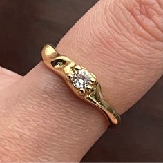 a close up of a person's hand wearing a gold ring with a diamond