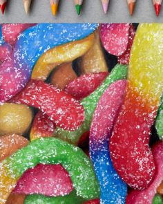 colored pencils are next to a drawing of colorful candies