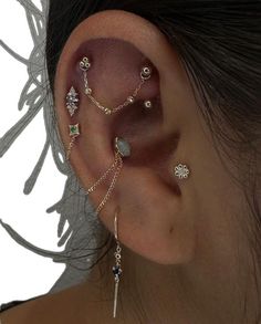 a woman's ear is adorned with different types of piercings and jewelry pieces