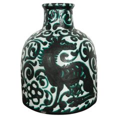 a black and white vase with green designs on it