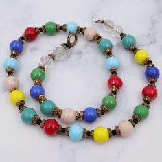 This antique necklace features gorgeous glass rainbow colored beads with brass spacers. This necklace measures 16.5" in length, with the beads measuring 9mm. The clasp and end loop have been replaced. This piece is in good antique condition with some wear. Vintage Czech Glass Beaded Necklaces With Round Beads, Vintage Czech Glass Beaded Necklace With Round Beads, Vintage Style Czech Glass Beaded Necklace, Vintage Multicolor Faceted Beads Necklace, Vintage Glass Beaded Necklaces With Colorful Beads, Retro Beaded Necklace With Colorful Round Beads, Vintage Multicolor Spacer Beads, Vintage Multicolor Single Strand Necklace, Retro Colorful Beaded Necklace