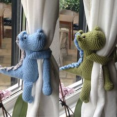 two crocheted teddy bears hanging from curtains