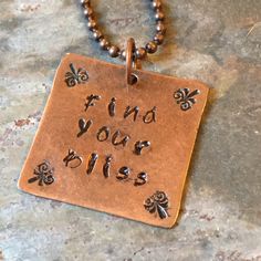 a necklace with the words find your bliss written on it and four clover charms attached to it