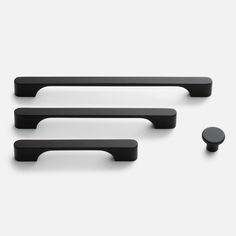 three black handles and two knobs on a white surface