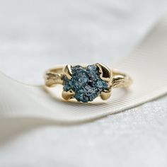 a blue diamond ring sitting on top of a white cloth