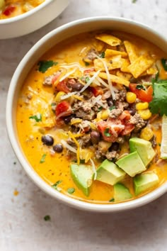 two bowls of mexican soup with tortilla chips and avocado on the side