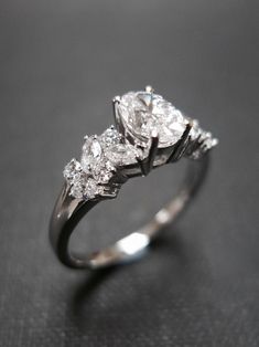 a three stone diamond ring on a black surface with the center setting in white gold