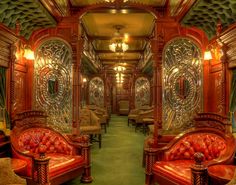 the inside of a train car with red leather seats and gold trimmings on the walls