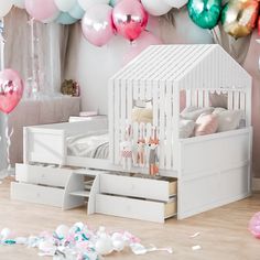 a white doll house bed with pink and green balloons in the background