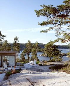 a house on top of a large rock next to the ocean with trees around it