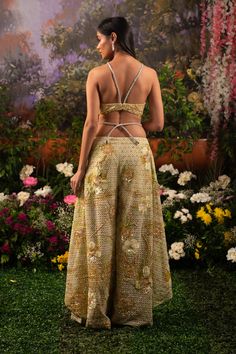 Behold the modern royalty through this Alana co-ord set. The ensemble comprises a bralette blouse paired with unconventional wide-legged pants and a heavily embellished cape. The monochrome outfit is highlighted with shiny sequins and beads crafting motifs of flowers and birds resonating a heavenly garden. Deep v-neck bralette attached with rhinestone embellished straps. The hook is attached to the back side of the blouse. Unconventional wide-legged pants with attached rhinestone straps at the w Elegant Summer Evening Lehenga, Festive Evening Palazzo Set With Cape Sleeves, Elegant Hand Embellished Palazzo Set For Evening, Glamorous Festive Sets With Cape Sleeves, Embellished Sleeveless Formal Sets, Evening Party Wear Sets With Cape Sleeves, Evening Sets With Cape Sleeves For Party Wear, Party Wear Sets With Cape Sleeves For Evening, Hand Embellished Sets With Cape Sleeves For Parties