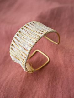 This chunky cuff bracelet is accentuated with woven raffia and gold thread. Wear with jeans and a tee to add some texture to a casual look. Raffia, thread, and brass Adjustable Made fair trade in India by one of our longstanding production partners Bohemian Cuff Bracelet For Spring, Spring Bohemian Cuff Bracelet, Bohemian Cuff Bracelets For Spring, Handwoven Gold Jewelry For Summer, Spring Adjustable Bohemian Cuff Bracelet, Handmade Gold Bracelets For Spring, Spring Bohemian Bangle Cuff Bracelet, Summer Gold Woven Jewelry, Spring Gift Jewelry In Natural Color