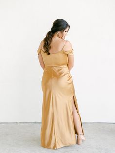 a woman in a gold dress is looking back at the camera and she has her hand on her hip