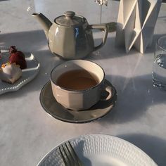 there is a cup of tea on the table next to some desserts and water glasses