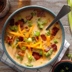 a bowl of soup with broccoli, cheese and bacon in it next to some celery