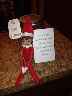 an elf holding a sign on top of a counter