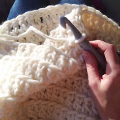 someone is knitting a blanket with scissors in their hand