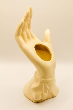 a white vase with a hand sticking out of it