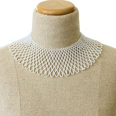 a white crochet necklace on a mannequin